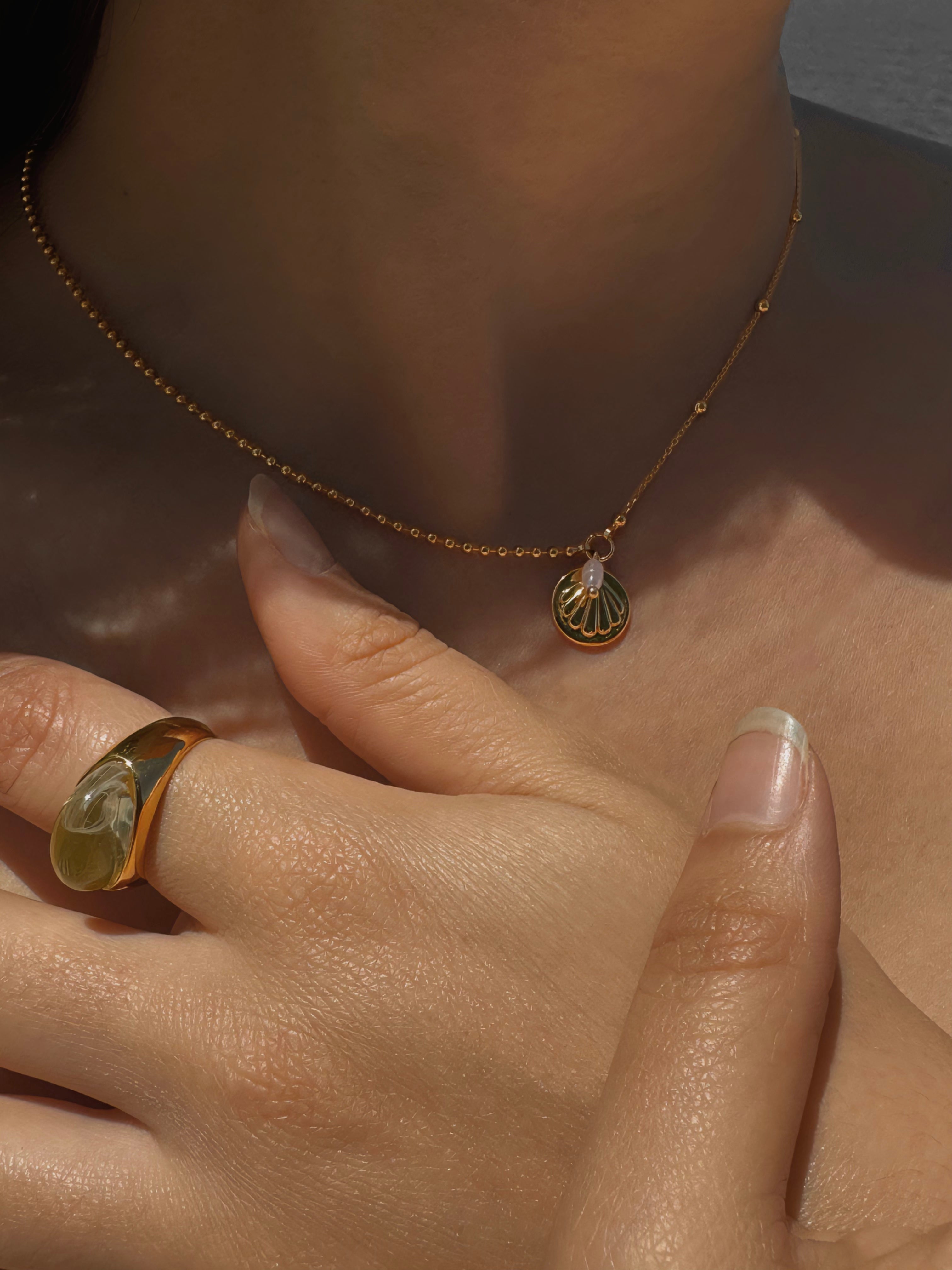 A British Instagram influencer model wears a chunky statement gemstone ring and dainty necklaces. Every gold hoops is selling in the new summer jewelry collection of Echok Jewellery. Explore for Summer everyday essentials accessories and vacation vibe right now in the UK.